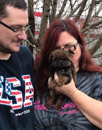 a man and woman are holding a small dog