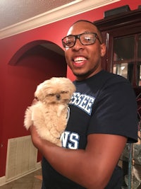 a man holding a small white dog in his arms