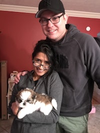 a man and woman posing for a picture holding a puppy