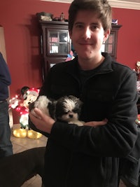 a young man holding a small dog in a living room