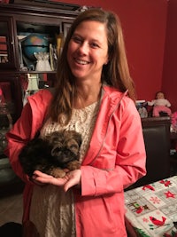 a woman holding a small puppy in a living room