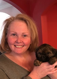 a woman holding a small brown puppy