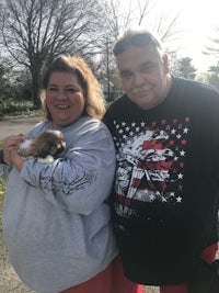 a man and woman posing for a picture holding a puppy