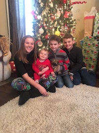 a family sits on the floor in front of a christmas tree