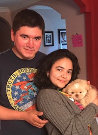 a man and woman posing with a small dog